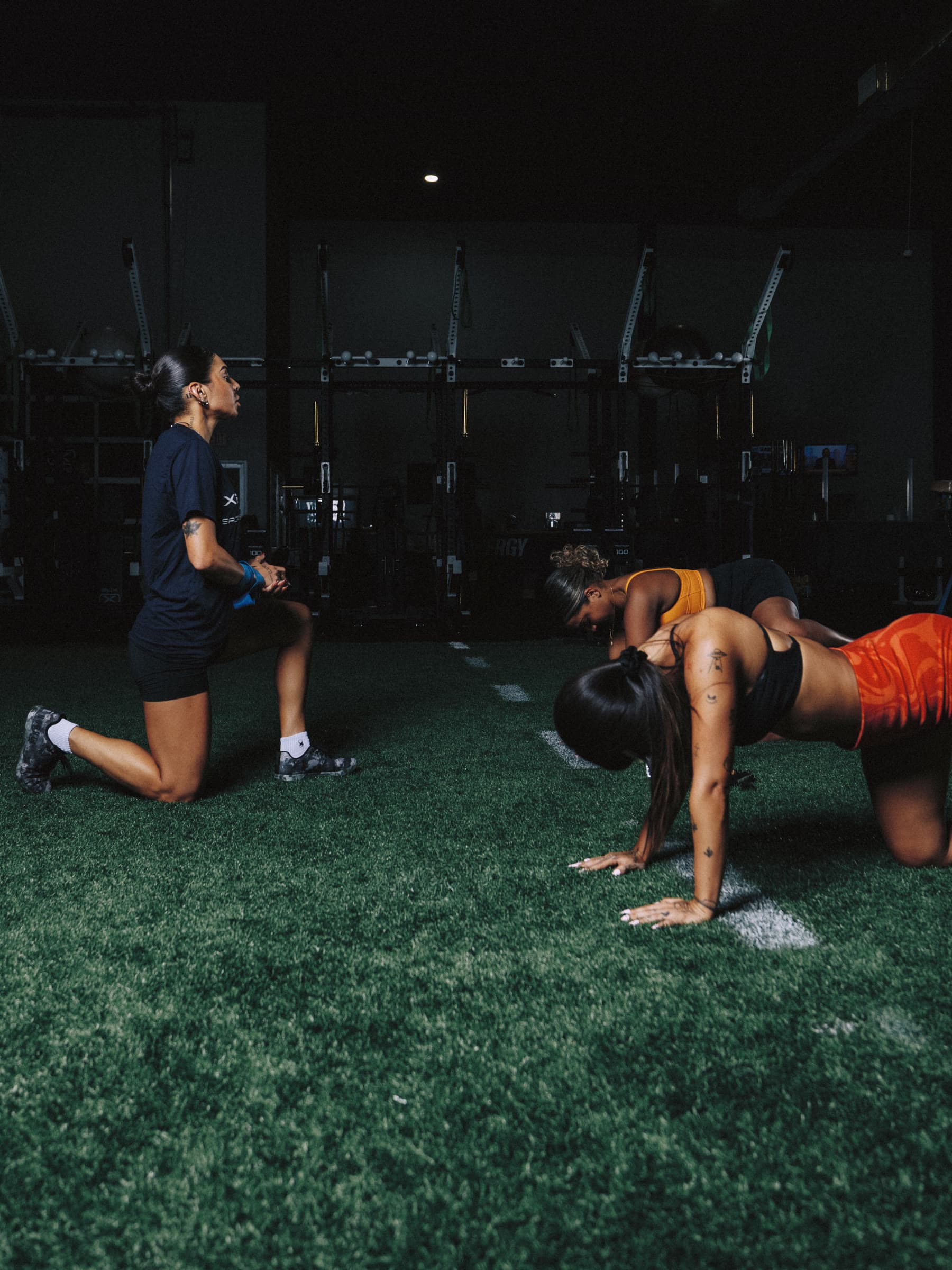 Nicole Mirani coaching two athletes through a warm-up on the turf.